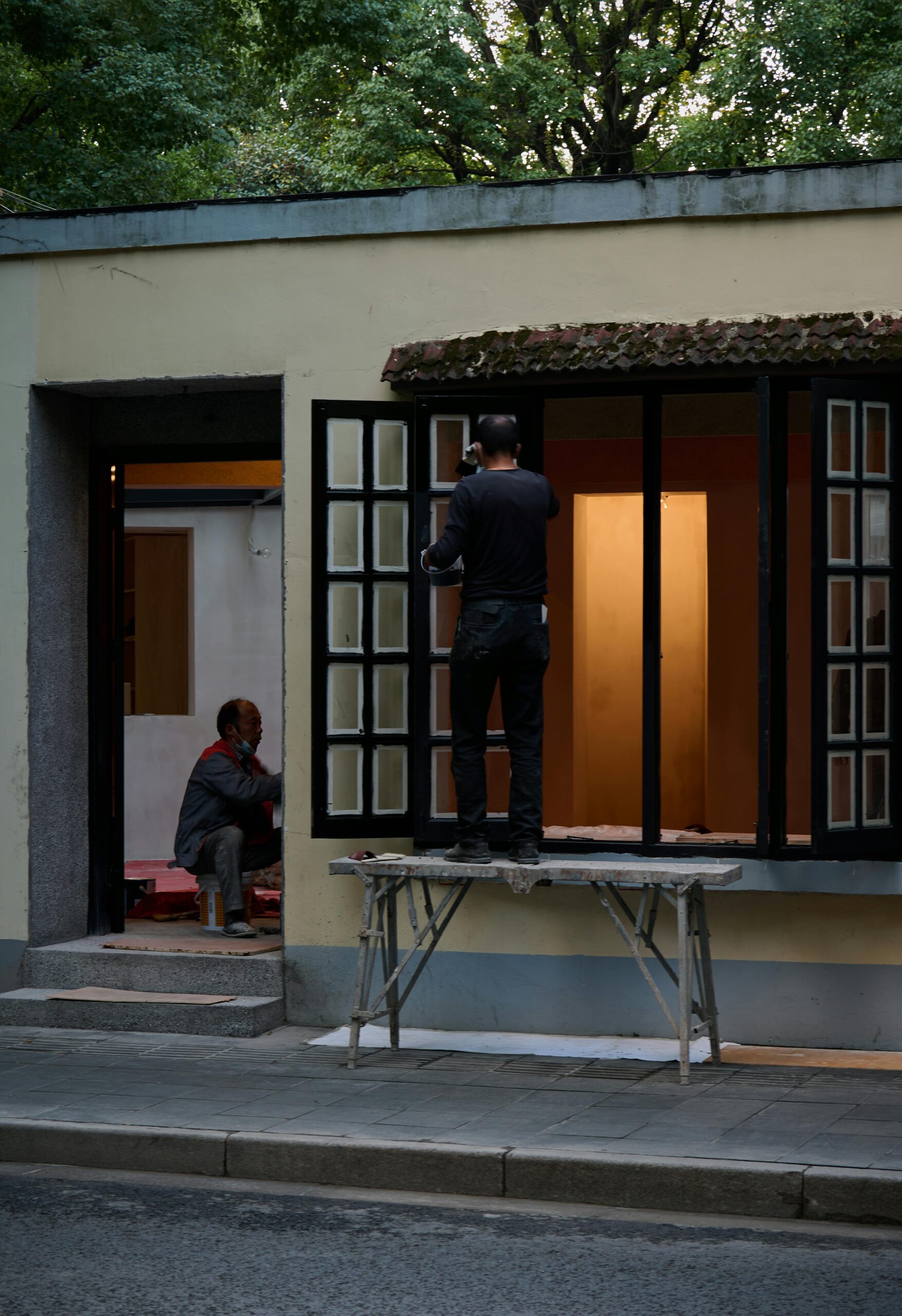 Two workers engaged in home renovation, focusing on repairing windows outdoors.