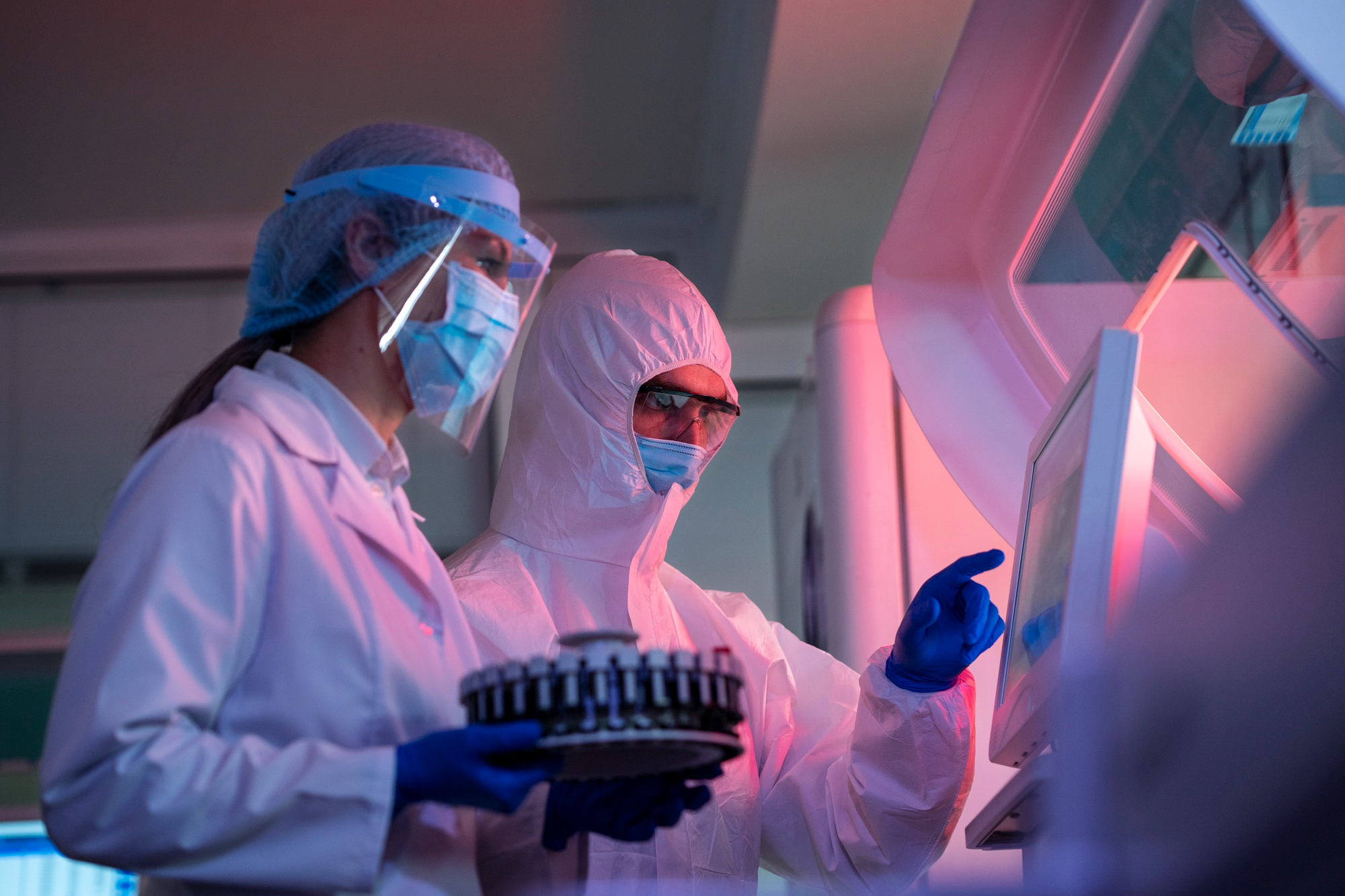 Scientists in full protective gear operating lab equipment.