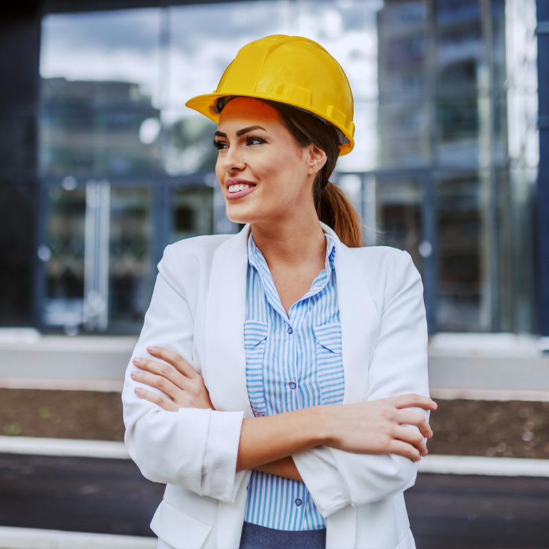 Confident female architect in a hard hat smiling at a construction site.